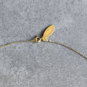 Close up of the gold personalisation tag on a By Wue birthstone necklace