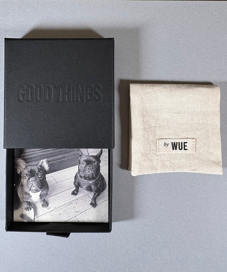 A black presentation box with a custom black-and-white dog photo on the inside lid, shown next to a beige linen pouch labeled 'by WUE' on a gray background.
