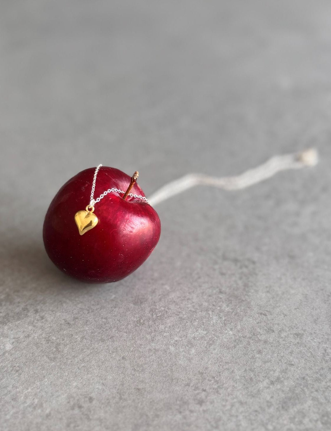Red cherry with a gold heart charm necklace.
