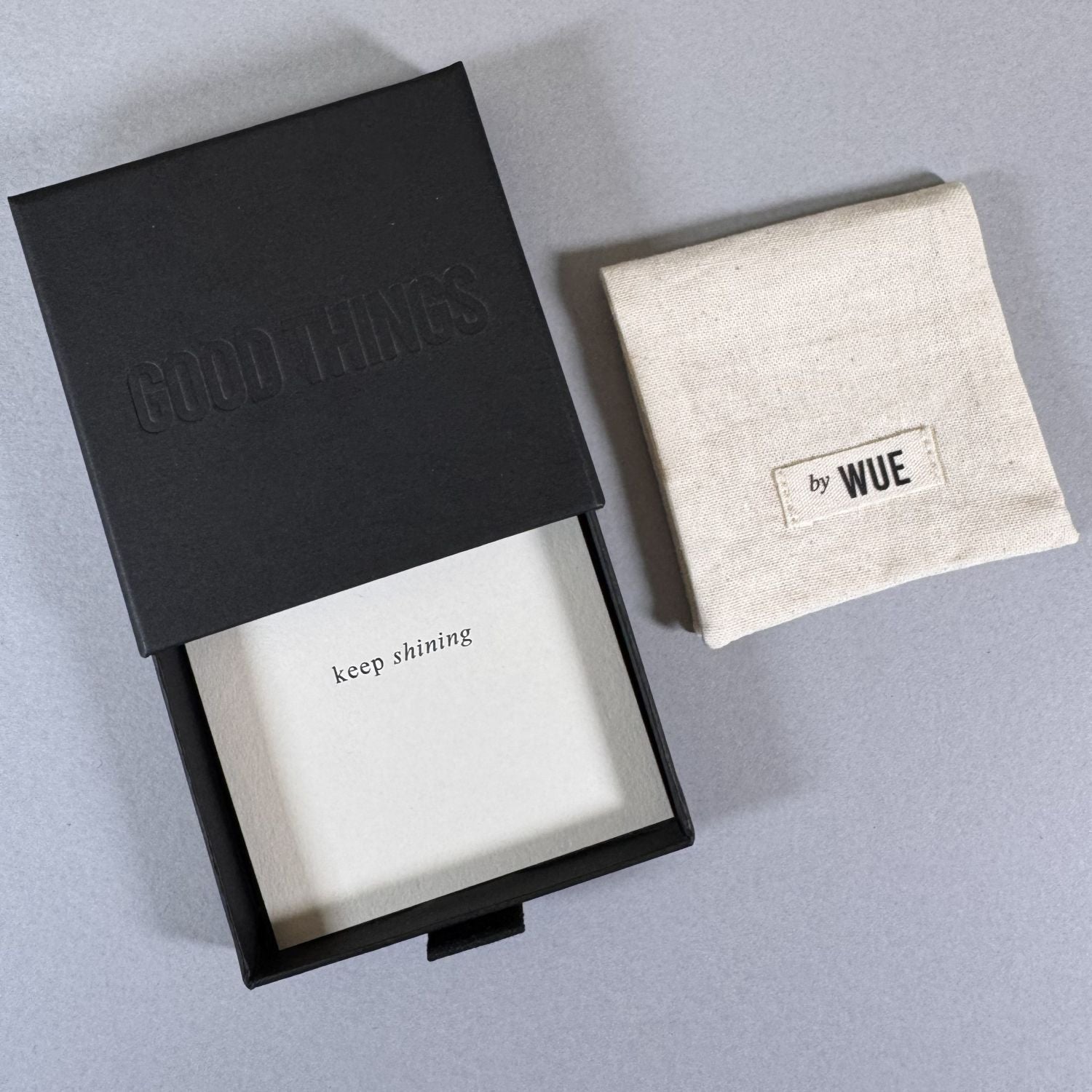 The Good Things gift box open with the printed card inside, and the cotton by Wue pouch alongside.