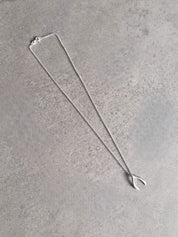 Sterling silver wishbone necklace laid out on a grey stone surface, showing the full chain and pendant.