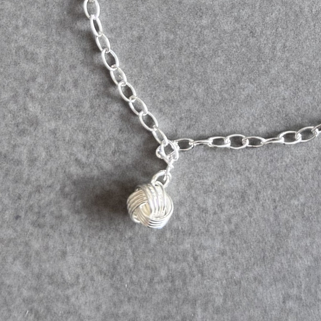 Close up of the friendship knot charm on a By Wue bracelet